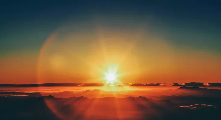 paysage avec un soleil qui se lève derrière les nuages 