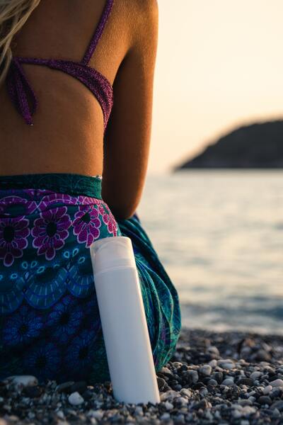 personne sur la plage avec un tube de creme solaire
